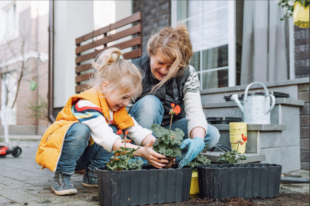 Grandma and granddaughter plant flowers during tick season.