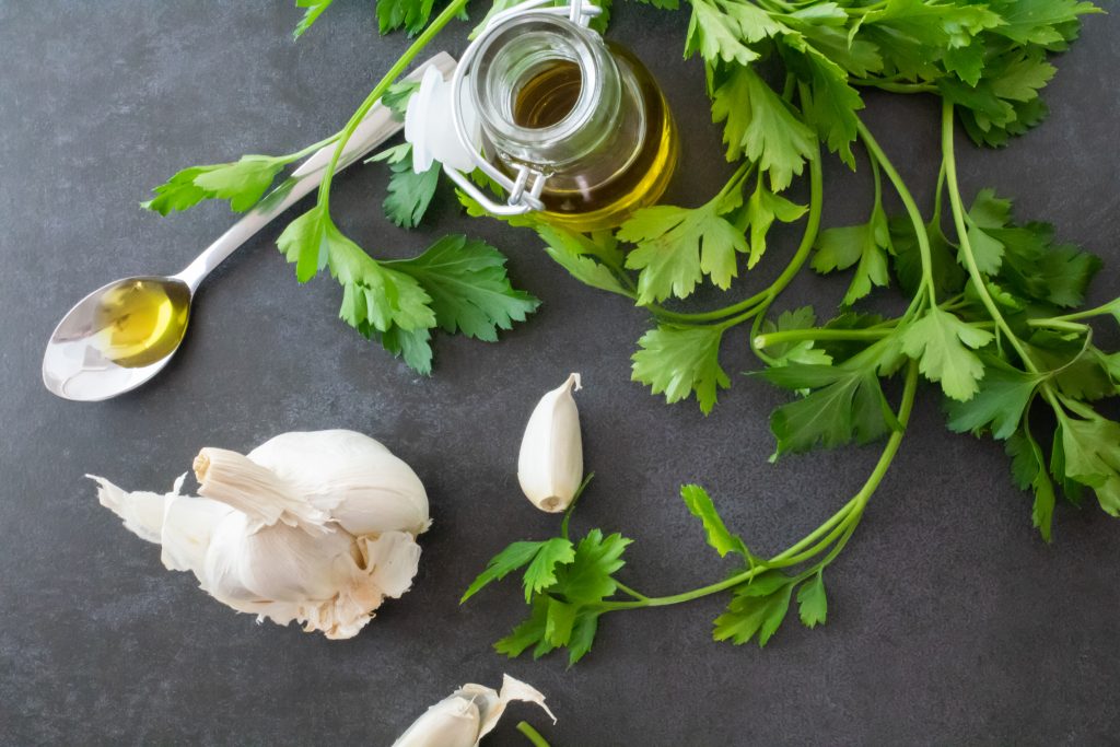 Garlic, herbs, and oil spread on a table for a parasite cleanse, photo by Healthy Living.