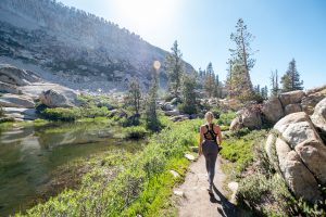 Woman hiking near lake and mountainside, credit Matt Bango.