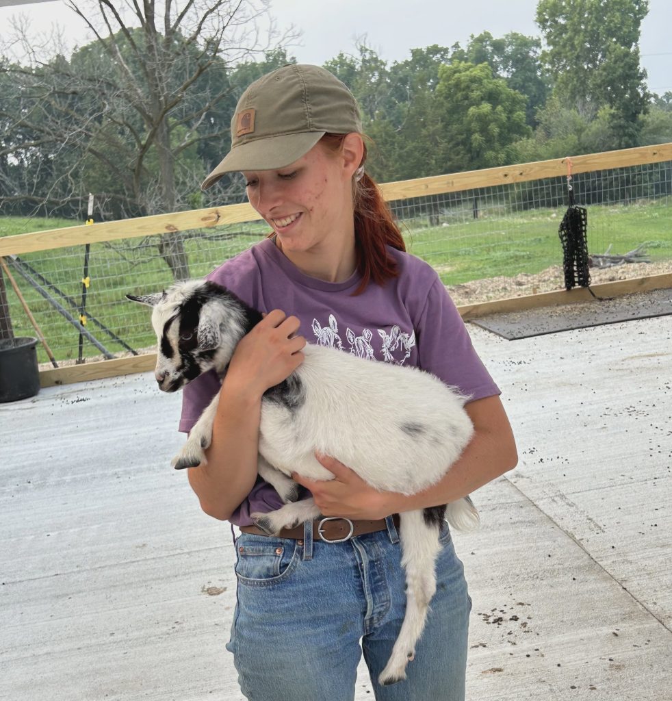 Wellness coach Victoria pictured holding a goat.